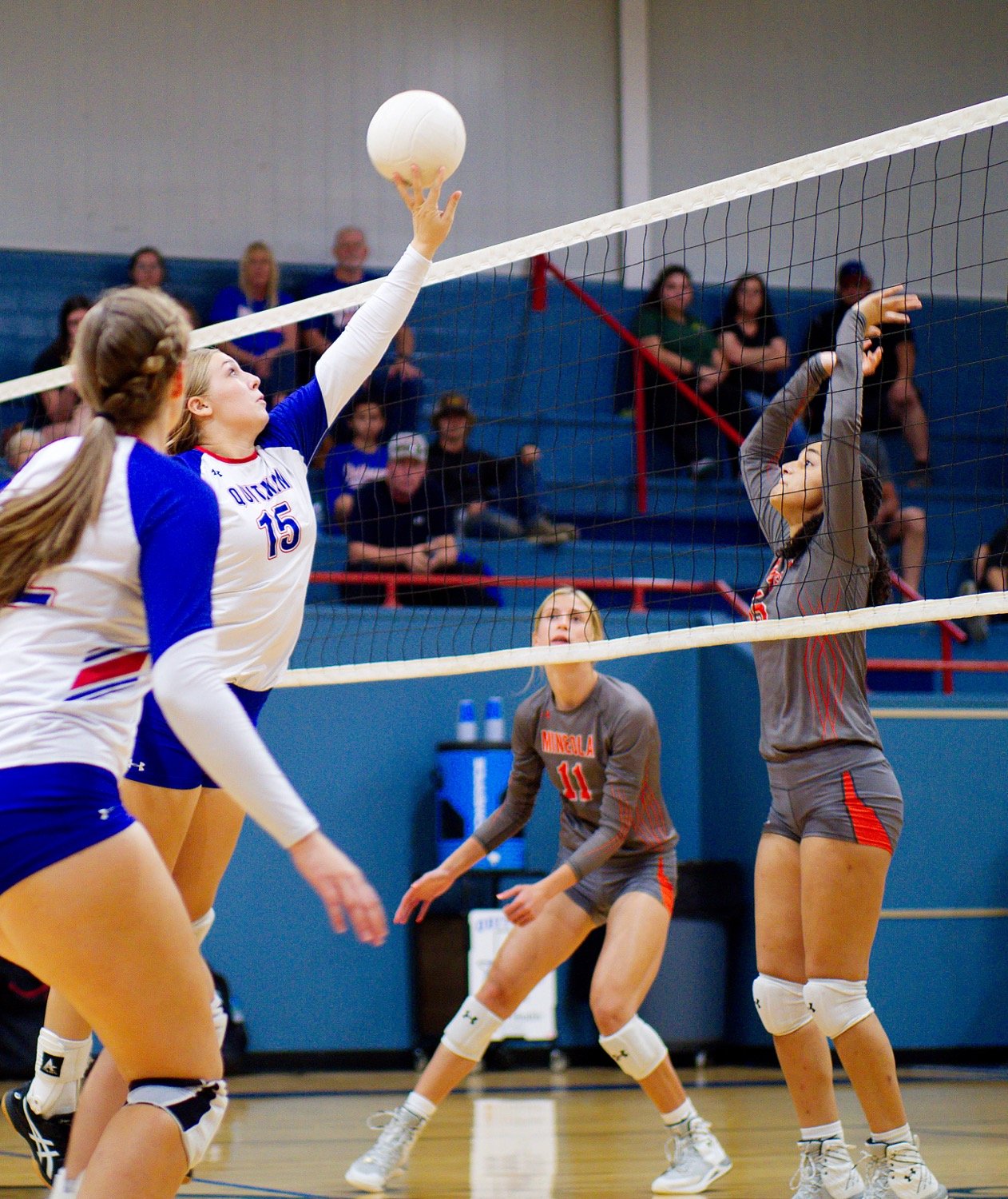 Annabelle Popek tips the ball over the net as Kyra Jackson readies to defend. [view more volleyball shots]